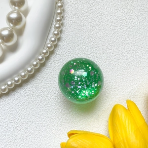Macro shot of green glitter phone grip with translucent resin ball and shiny sequins