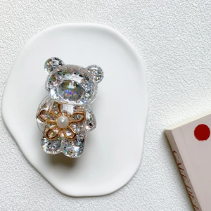 Detailed view of bear phone grip with colorful sequins and small golden flower accessory