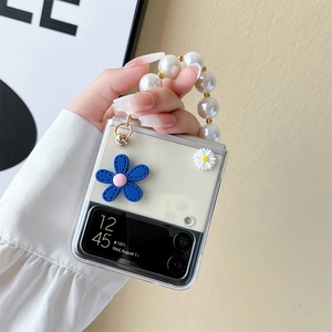 Detail of transparent phone case with blue floral charms and large white pearl handle