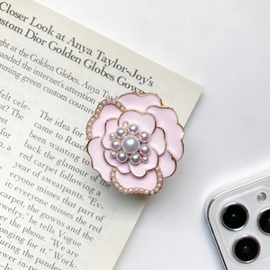 Detailed close-up of a pink floral phone grip with elegant pearls and enamel petals