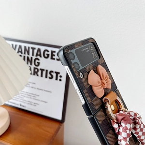 Detail of checkered leather folding phone case with pink bow and ribbon charm