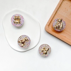 Detail shot of four bear and bow designs with colorful rhinestones on gold mounts