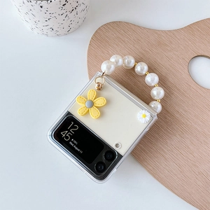 Detail of transparent phone case with white daisy, pearl handle, and yellow flower charm