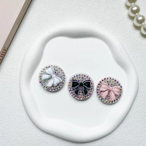Close-up of rhinestone phone grips with pearl bows in white, black, and pink colors