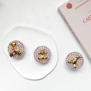 Detail shot of three gold teddy bear phone grips with sparkling rhinestones on a tray