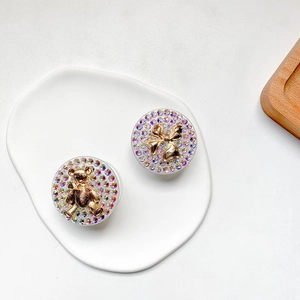 Close-up of bear and bowknot phone grips with colorful rhinestones on a white plate