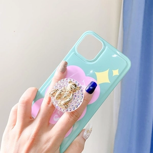 Green rhinestone bear phone grip and floral case shown in hand for stylish use