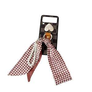 Checkerboard pattern folding case for Z Flip with heart detail, bow, and pearl strap
