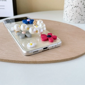 Detail of Samsung Z Flip case featuring 3D floral accents and a white pearl handle