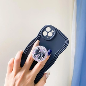 Detail of navy blue wavy phone case featuring a glittery bow popsocket grip