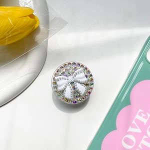 Detailed view of rhinestone and pearl bow phone socket grip on a mint green case