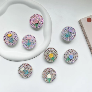 Detailed view of seven colorful rhinestone flower phone sockets on a white display tray