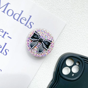 Detail of a round phone socket with a black bow, white pearls, and gradient rhinestones