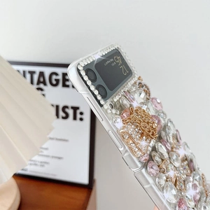 Detail of luxury rhinestone bow and pearl charms on Galaxy Z Flip case with gold chain