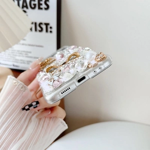Close-up of luxury phone case with rhinestones, pink crystals, and pearls on a clear cover
