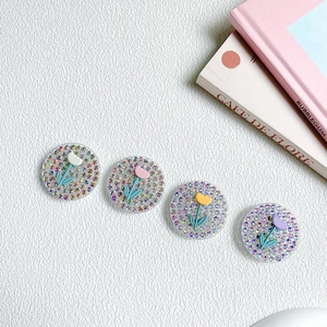 Detail view of four floral rhinestone phone grips in pink, purple, white and yellow