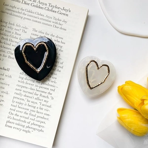 Close-up of heart-shaped hair clips in black and white marble with gold metal edges