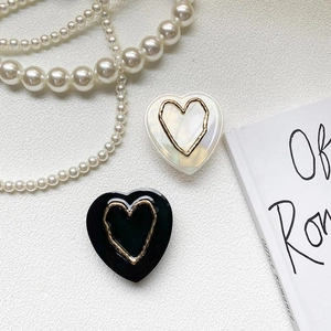 Detail of heart-shaped phone grip with iridescent shell texture and gold metal heart inlay