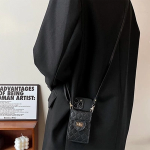 Chic black quilted leather crossbody phone bag with gold twist lock on black blazer