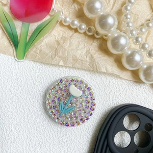 Detail of a round pop socket with sparkling rhinestones and a white tulip floral design
