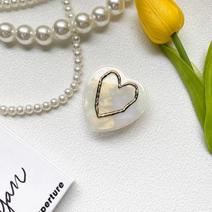 Macro shot of heart-shaped phone grip with pearlescent finish and golden metallic edge