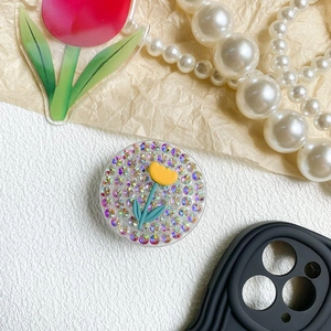 Sparkly rhinestone phone grip with yellow tulip flower on a white textured background