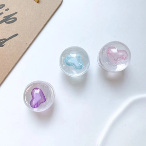 Detail showing three clear heart-shaped phone stands in pink, lilac, and sky blue