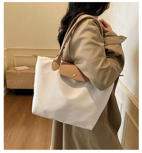 Detail of minimalist tote bag with leather flap and metal snap closure on canvas