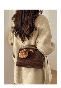 Detail of leopard print bucket bag with metal twist lock and cute plush charm detail