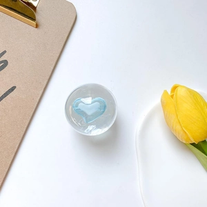 Close-up of a clear crystal ball phone socket with a light blue heart inside on white background