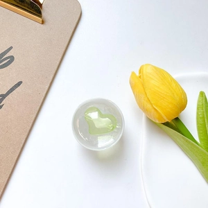 Detail of a green heart-shaped crystal phone socket holder on a minimalist desk setting