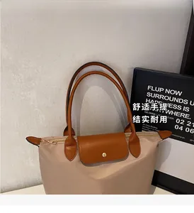 Macro shot of beige nylon tote featuring premium brown leather handles and gold metal snap
