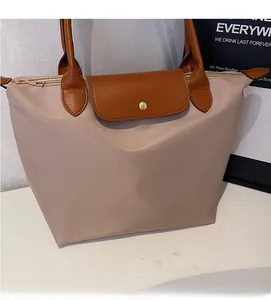 Detail of light khaki waterproof nylon tote with brown leather handles and snap button flap