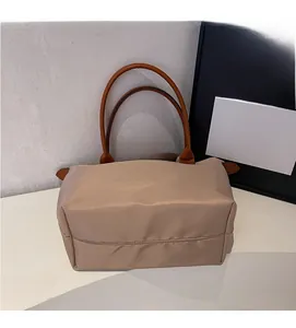 Detail of khaki nylon tote bag showing high-density fabric and brown leather handles
