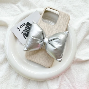 Détail d'une coque de téléphone en cuir blanc crème avec un grand nœud argenté en 3D