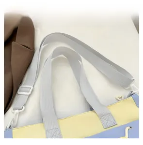 Detail of canvas tote bag showing dual handles and adjustable nylon shoulder strap