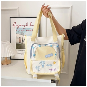 Détail du sac en toile avec patchs brodés, poche en filet et fermeture à boucle