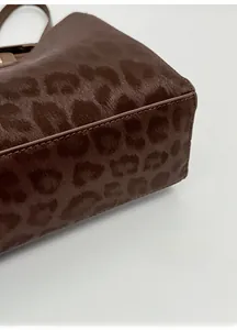 Macro shot of the sturdy base and faux leopard fur texture of the brown tote bag
