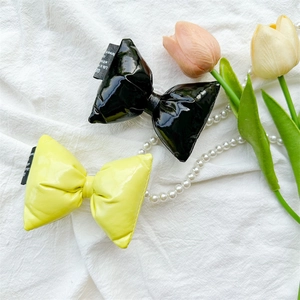 Gros plan de pinces à cheveux papillon 3D en cuir brillant noir et jaune avec étiquettes