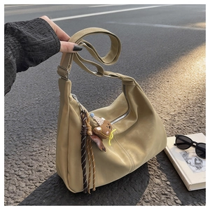 Detail of khaki hobo bag featuring matte faux leather and a cute brown bear charm