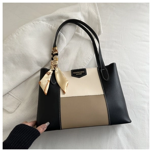 Close-up of tricolor patchwork tote bag with fashion logo and decorative silk scarf