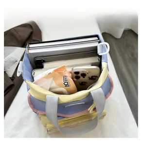 Spacious interior of a tricolor canvas bag showing storage for a tablet and books