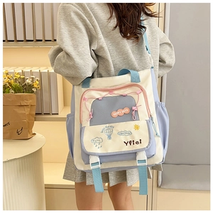 Détail du sac bandoulière en toile avec poches bleues et broderie Happy Days élégante