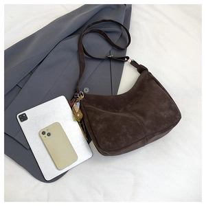 Deep brown suede crescent bag shown with tablet to demonstrate large capacity