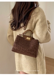 Detail of leopard print shoulder bag with gold hardware and brown leather handle