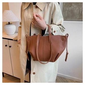 Detail einer braunen Handtasche aus Leder mit Litschimuster und Kordelzug-Design