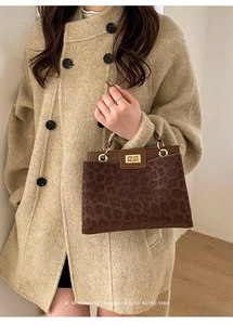 Close-up of leopard print handbag with golden buckle and textured fabric finish