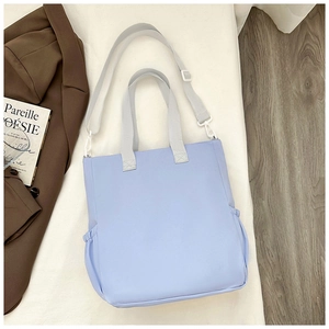 Detail of light blue nylon tote bag showing side pocket and adjustable shoulder strap