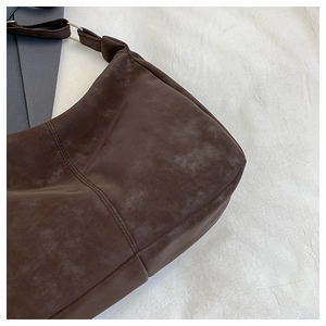 Macro shot of dark brown suede texture and metal ring buckle on the shoulder bag