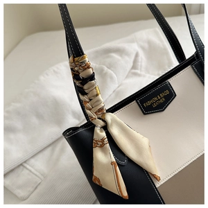 Detail of tricolor tote bag featuring contrast stitching and elegant silk scarf handle wrap